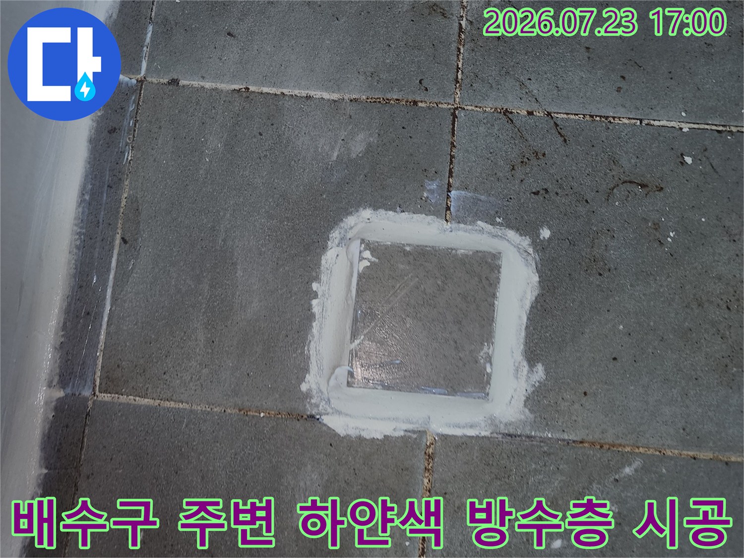 회색빛 욕실 타일 중앙에 위치한 배수구 테두리를 방수제로 밀봉 처리한 사진