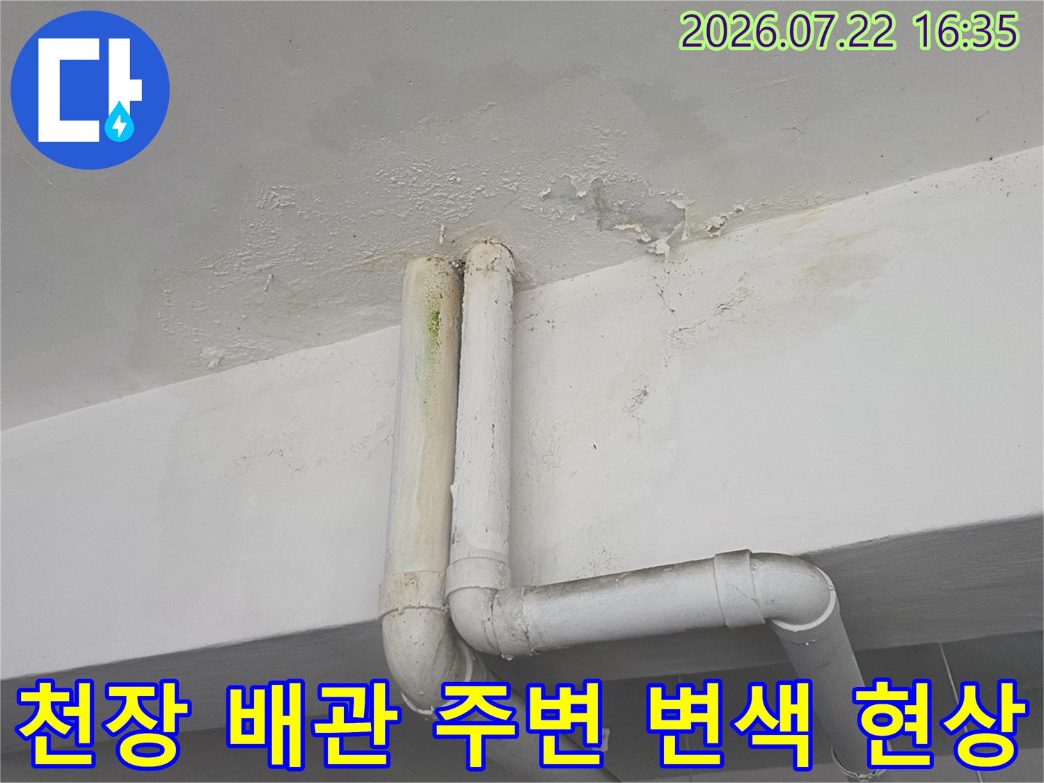 두 개의 흰색 PVC 배관과 그 상단 천장면의 누수로 인한 변색 및 박리 상태