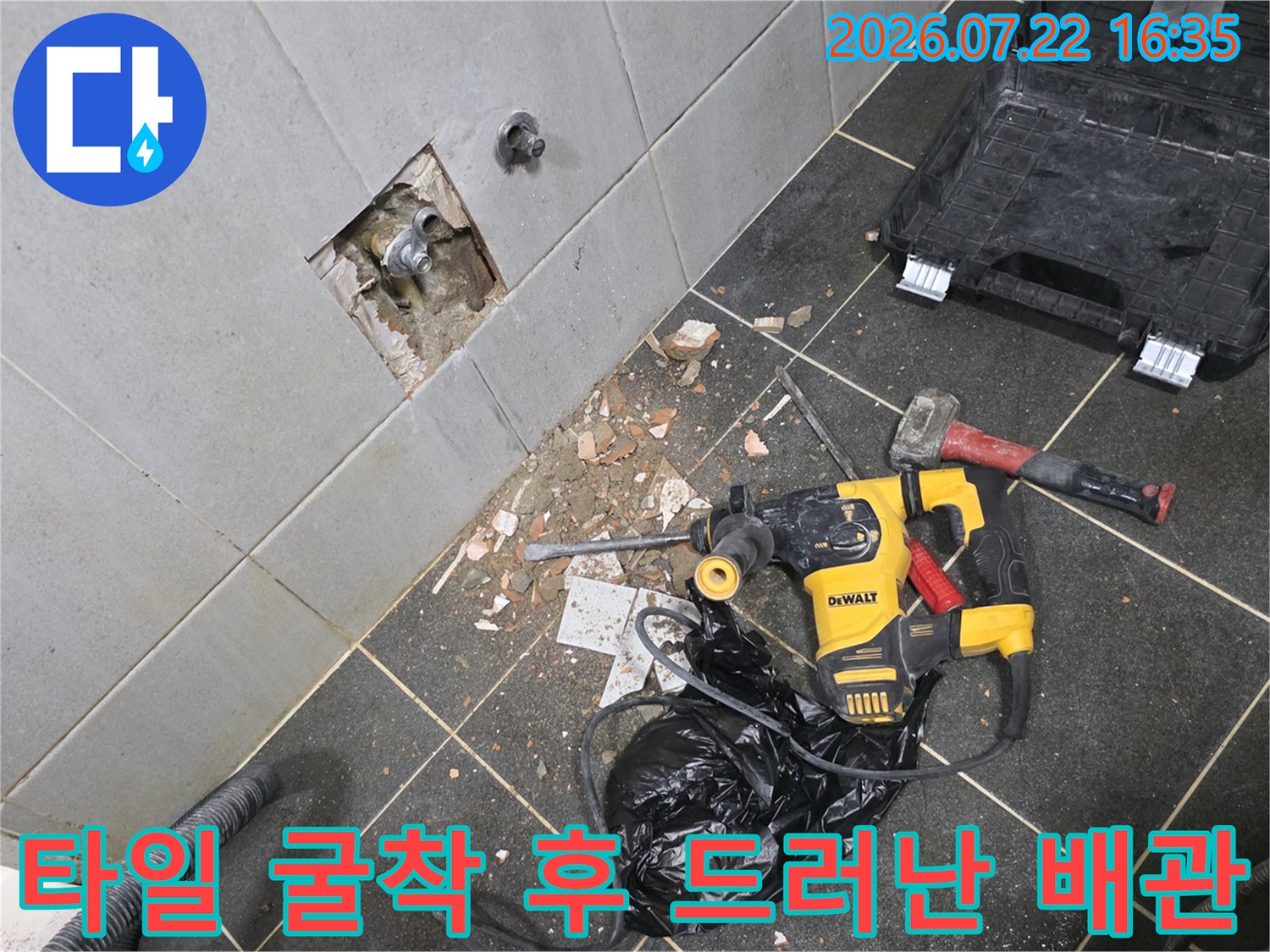 배관 수리를 위해 타일을 일부 파낸 벽면과 바닥에 놓인 노란색 전동공구