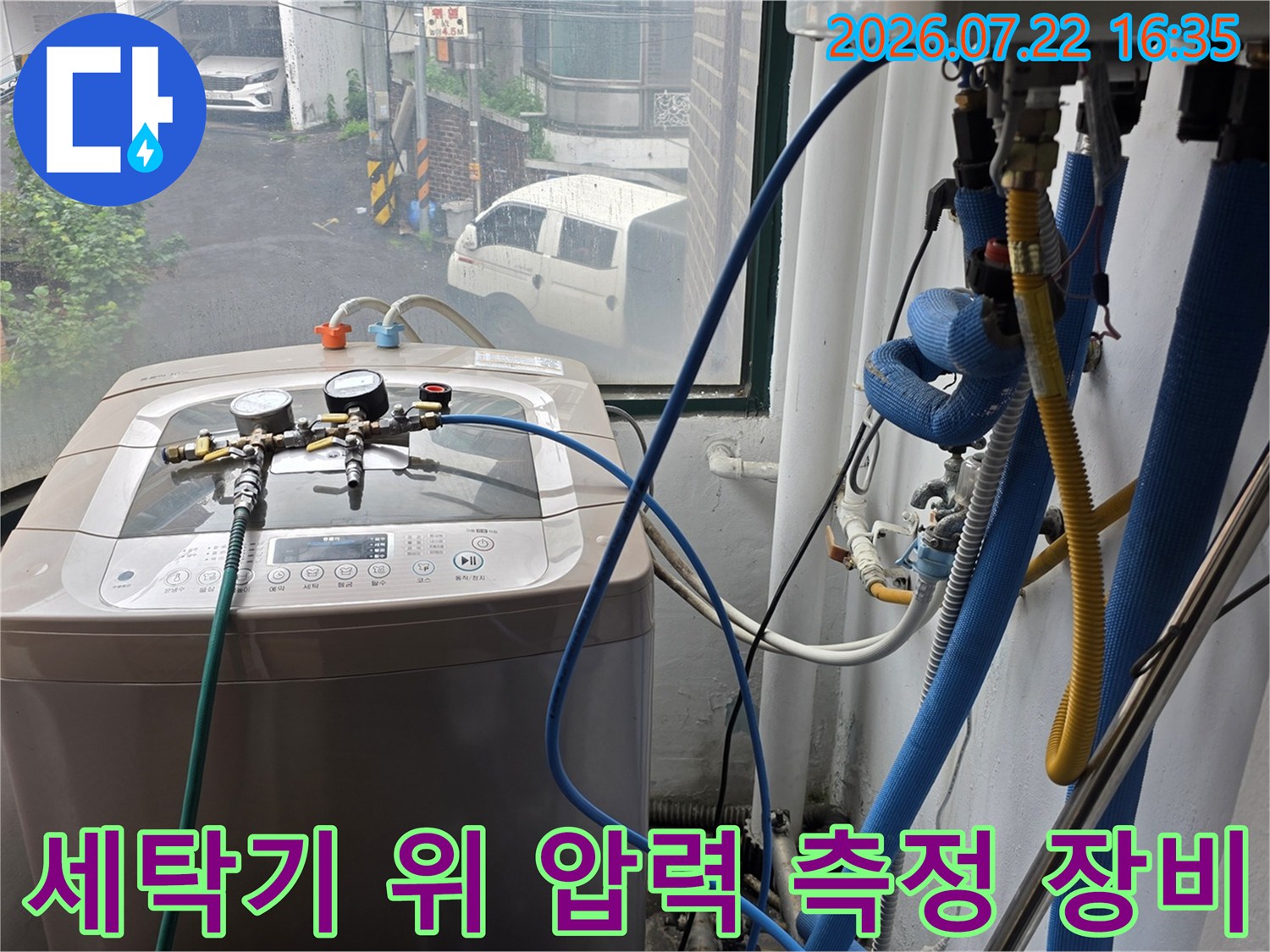 세탁기 위에 설치된 정밀 압력 게이지와 파란색 연결 호스-누수 탐지를 위한 공압 테스트 장면