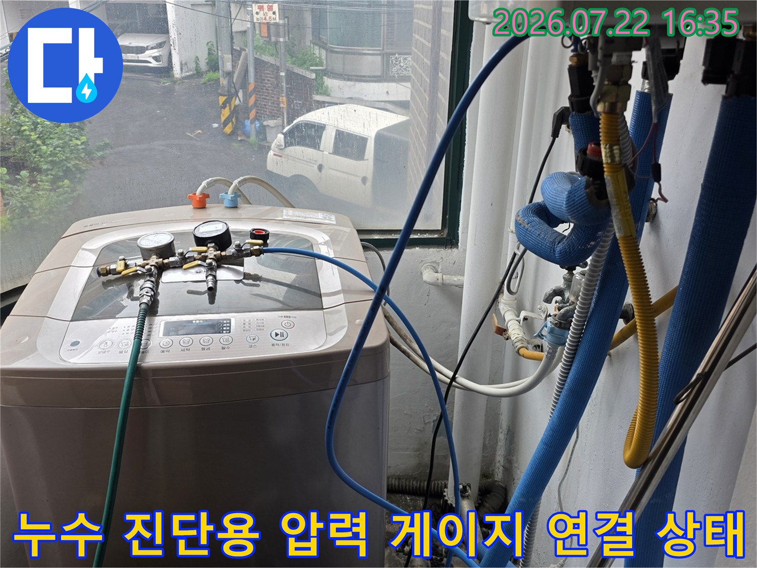 파란색 고무 호스가 세탁기와 배관 시스템에 연결되어 압력을 측정하는 장면