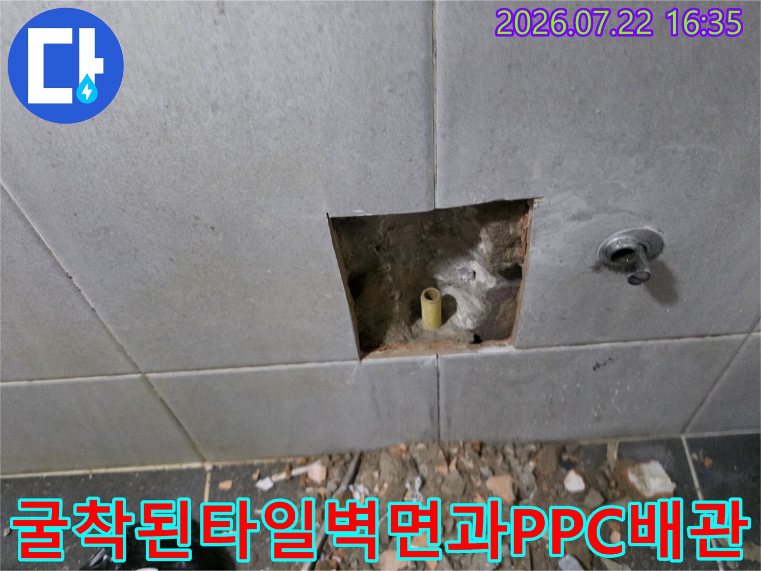 회색-타일-벽면을-일부-제거하여-내부에-매립된-노란색-수도관을-노출시킨-상태