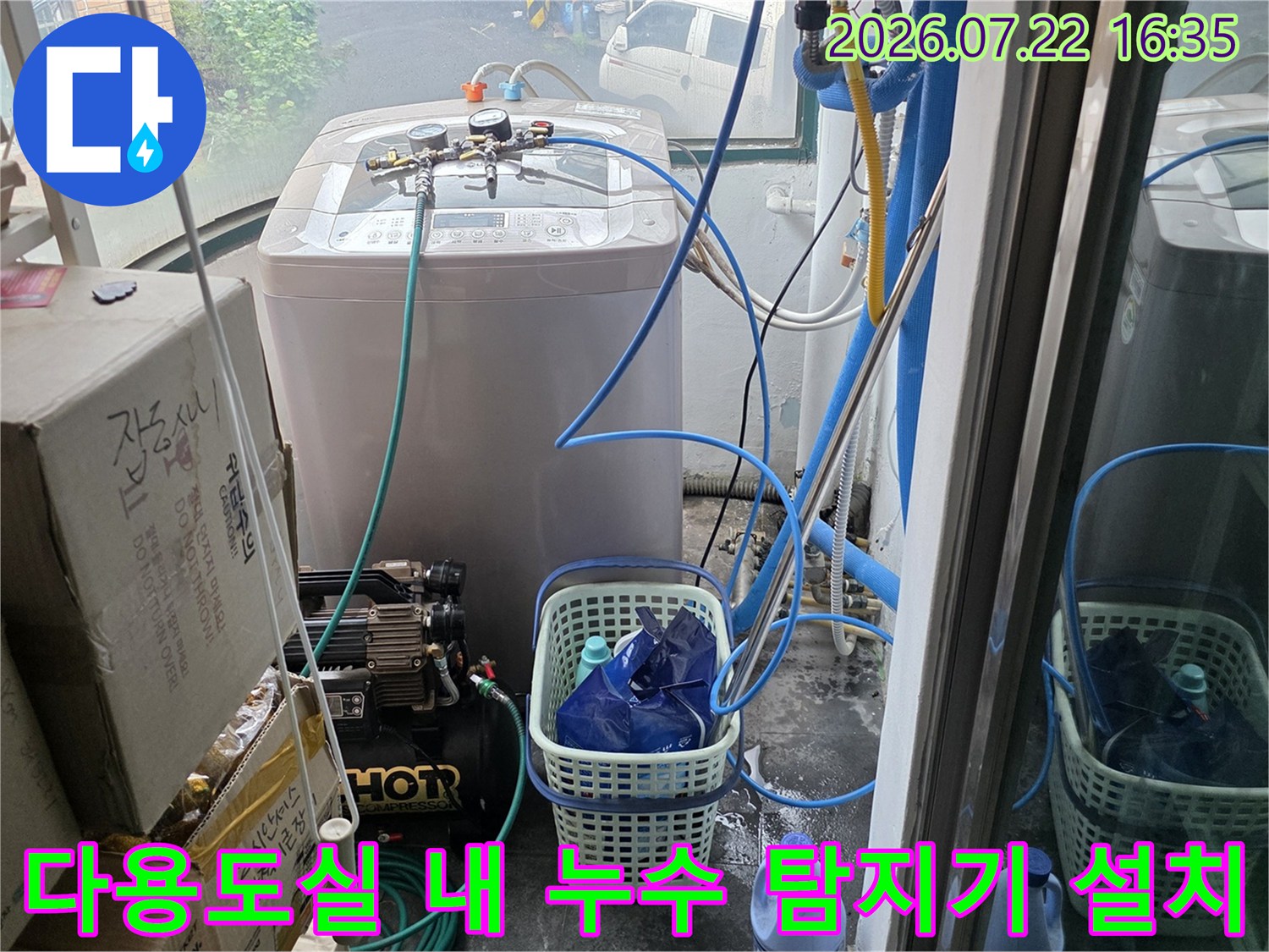 흰색 가전제품 옆에 배치된 누수 탐지 장비와 파란색 연결 호스들
