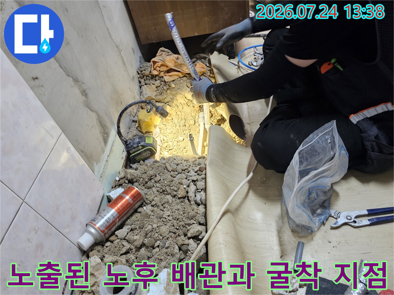 바닥을 파내어 드러난 부식된 배관 주변으로 작업 도구와 보양재가 놓여 있는 모습