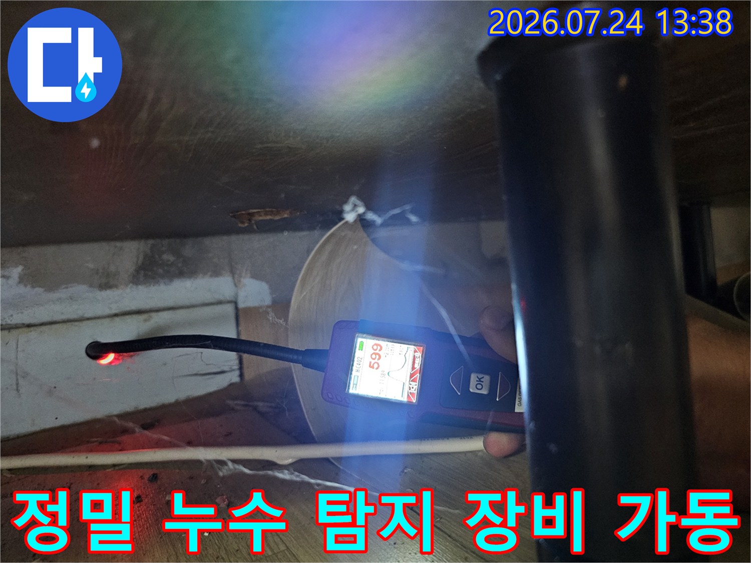 어두운 배관 주변에서 디지털 가스 탐지기를 사용하여 수치를 측정하고 있는 장면