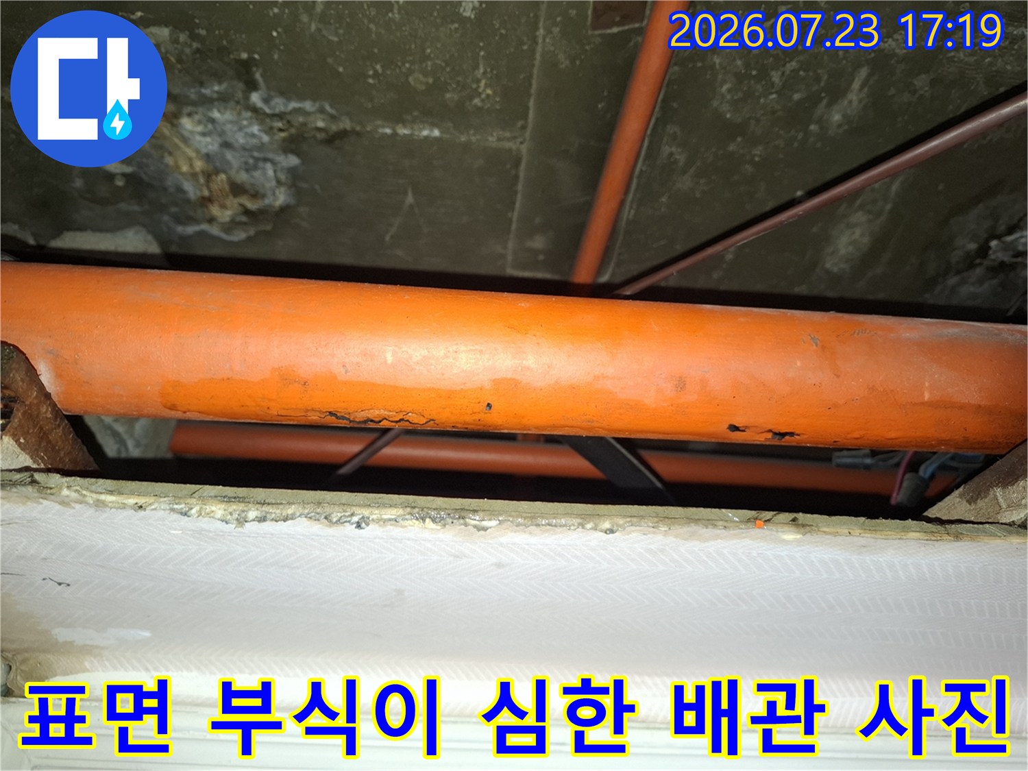 표면이 오염되고 부식되어 내구성이 약해진 주황색 수도 배관의 근접 촬영 이미지