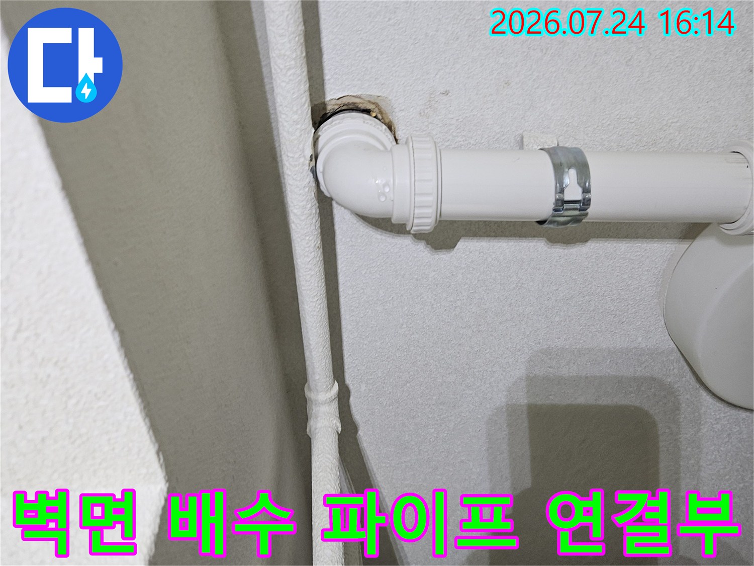 벽면에 고정된 하얀색 PVC 배수관과 연결 부위 점검 장면