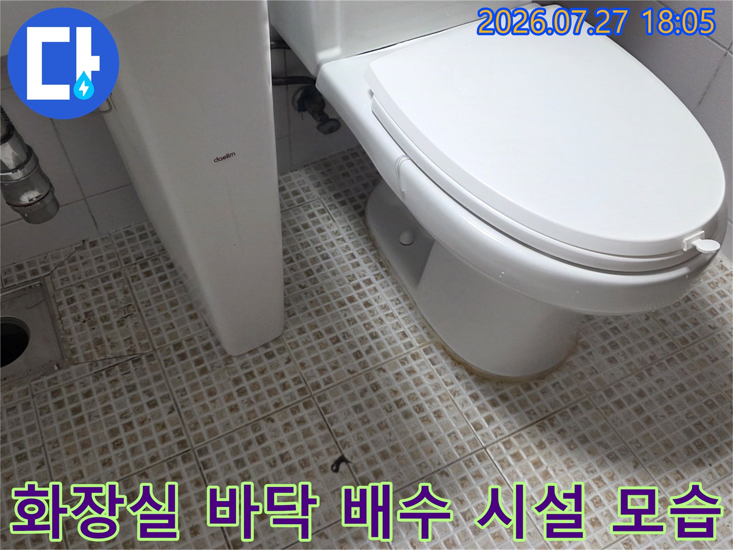 욕실의-흰색 타일 바닥 위에 설치된 배수구와 양변기가 함께 찍힌 사진