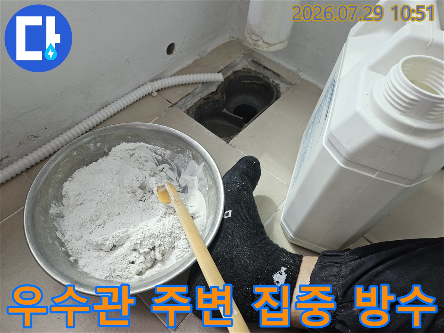 작업자가 우수관과 연결된 배수구에 회색 방수 크림을 펴 바르는 모습