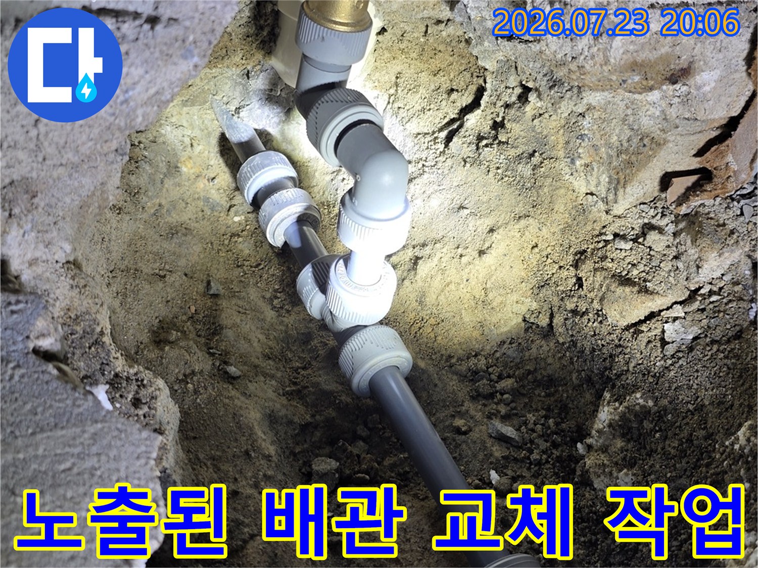 굴착된 벽면을 따라 노출된 수도 배관과 새 부속으로 연결된 배관의 모습