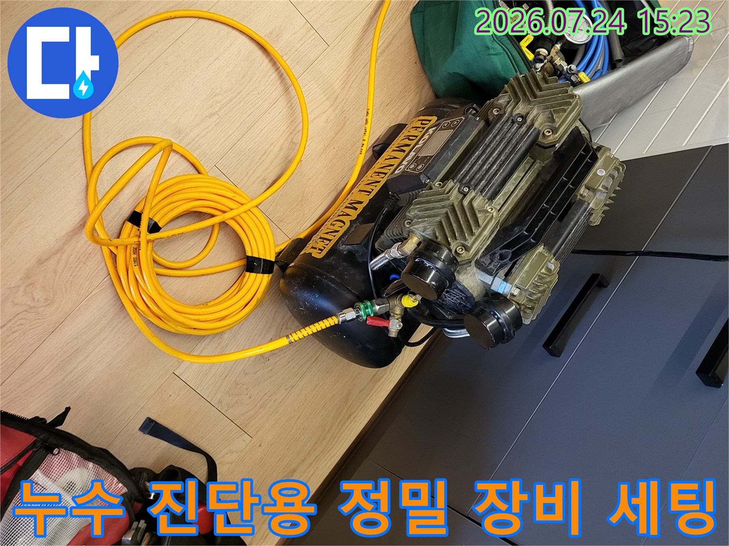 바닥에 배치된 누수 탐지용 컴프레셔와 압력 게이지-노란색 연결 호스
