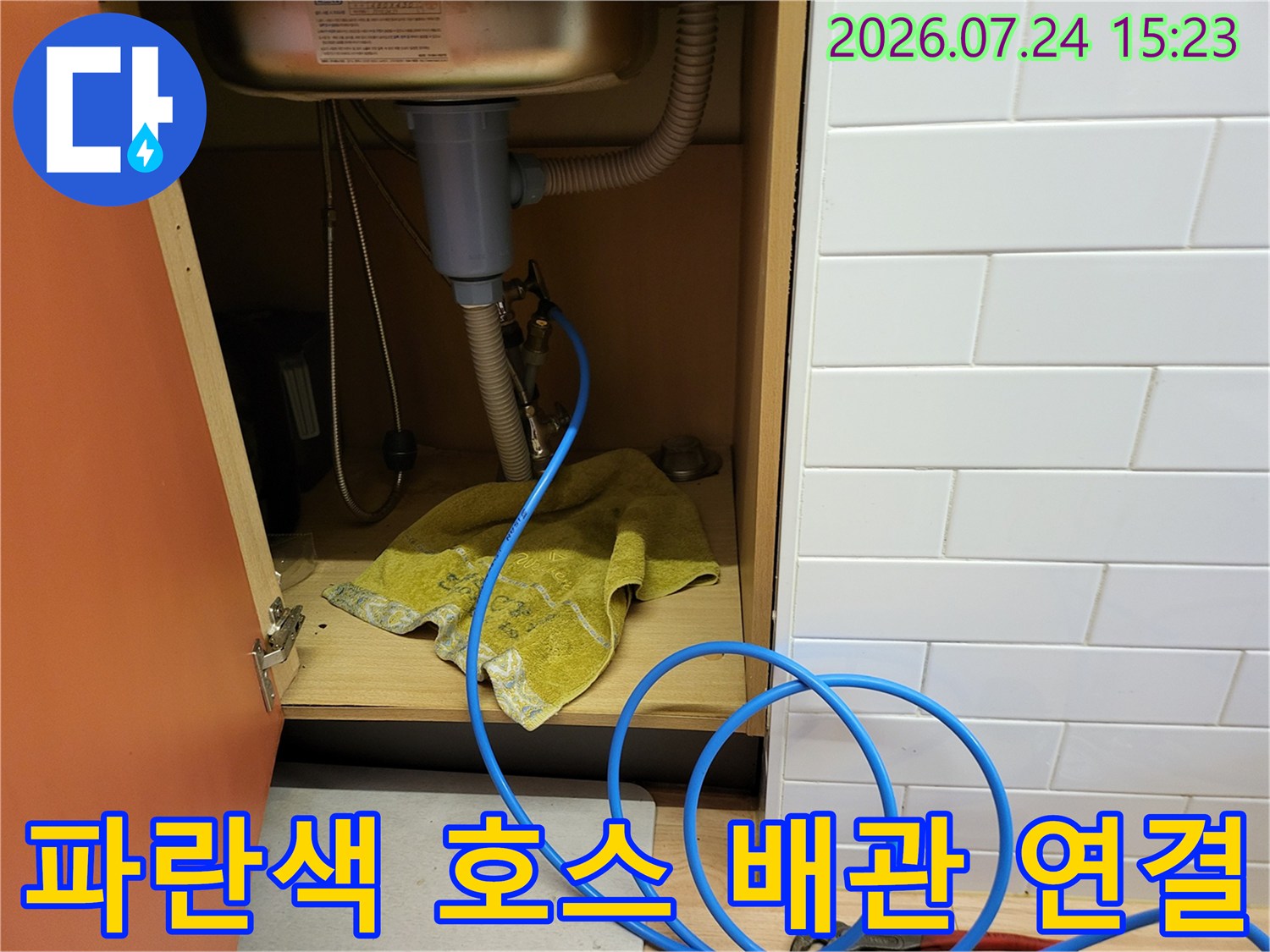 싱크대 아래쪽 배관에 파란색 특수 호스를 연결하여 압력 테스트를 진행 중인 현장 사진