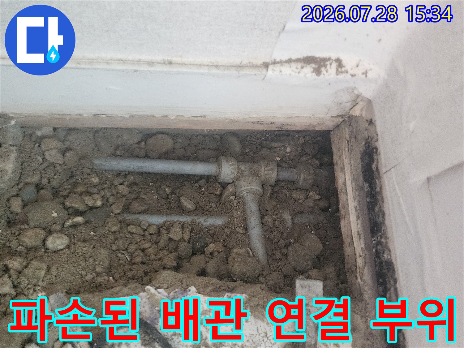 흙 속에 파묻힌 회색 수도관과 연결 부속 노출 모습
