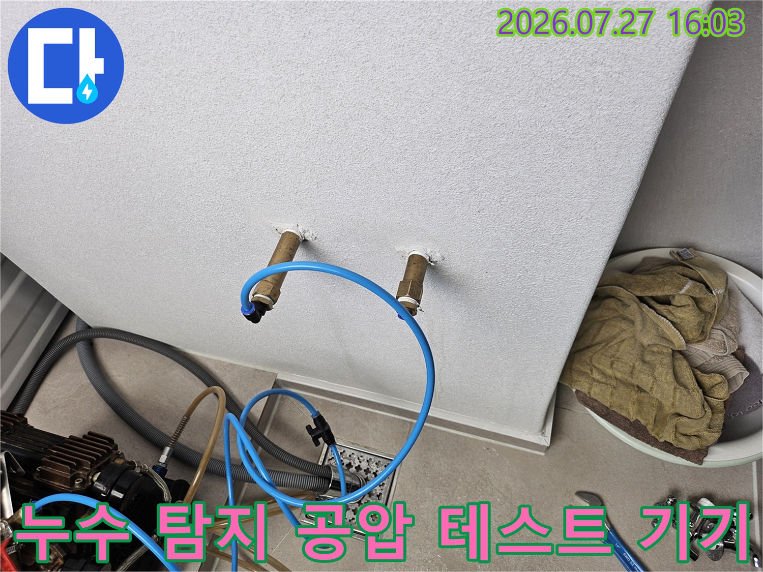 벽면에 설치된 수도 배관 밸브와 파란색 공압 호스가 연결된 모습