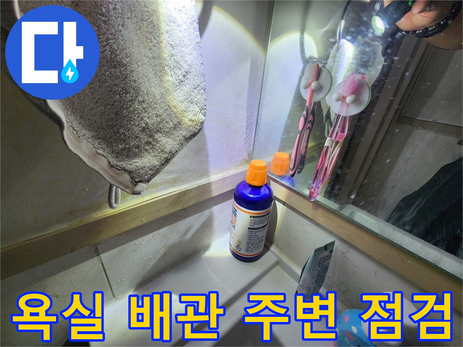 세면대와 벽면 타일 경계 부위의 누수 징후를 살피는 장면