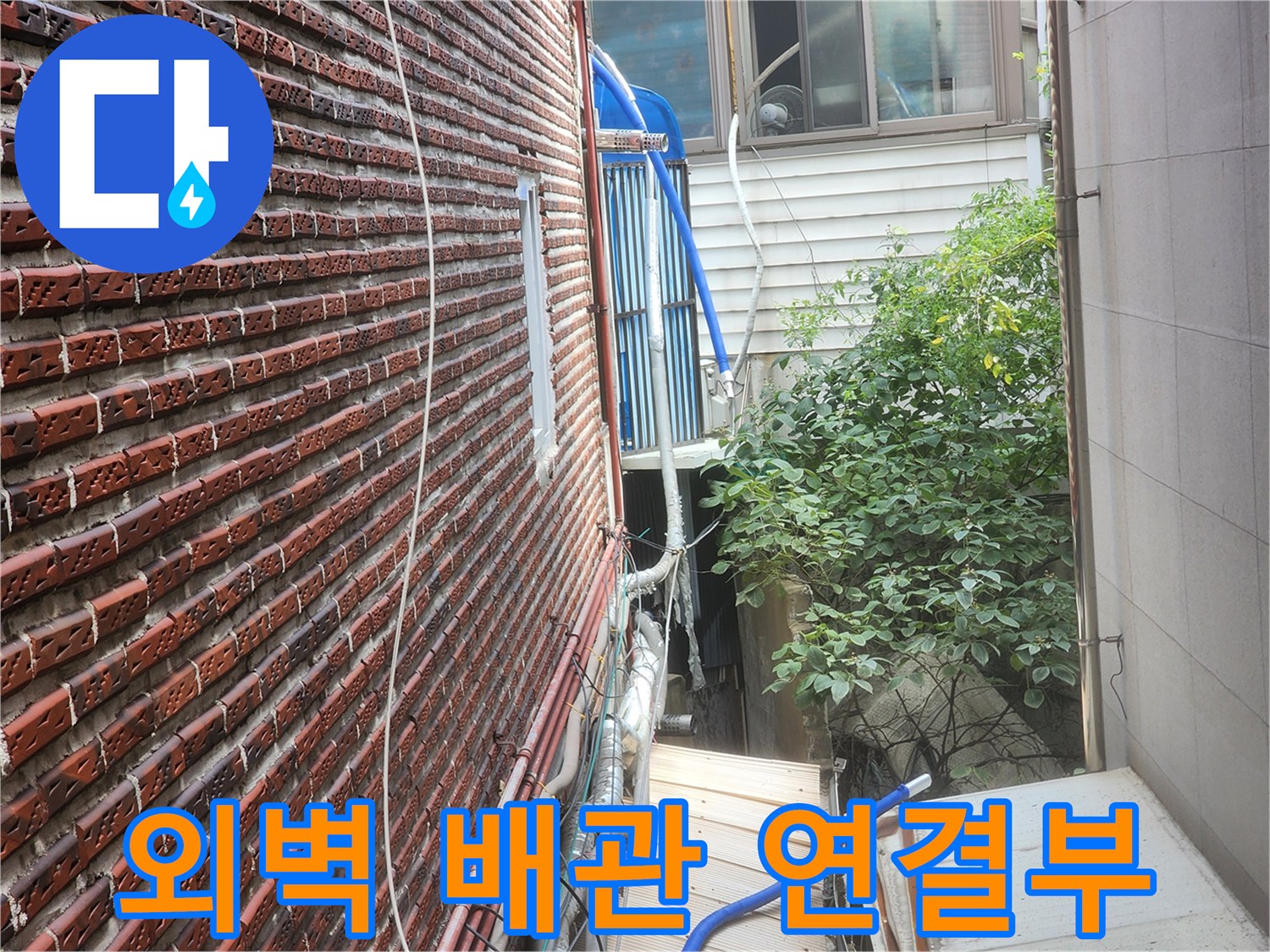 벽돌 외벽에 설치된 외부 노출형 수도 배관 상세 모습