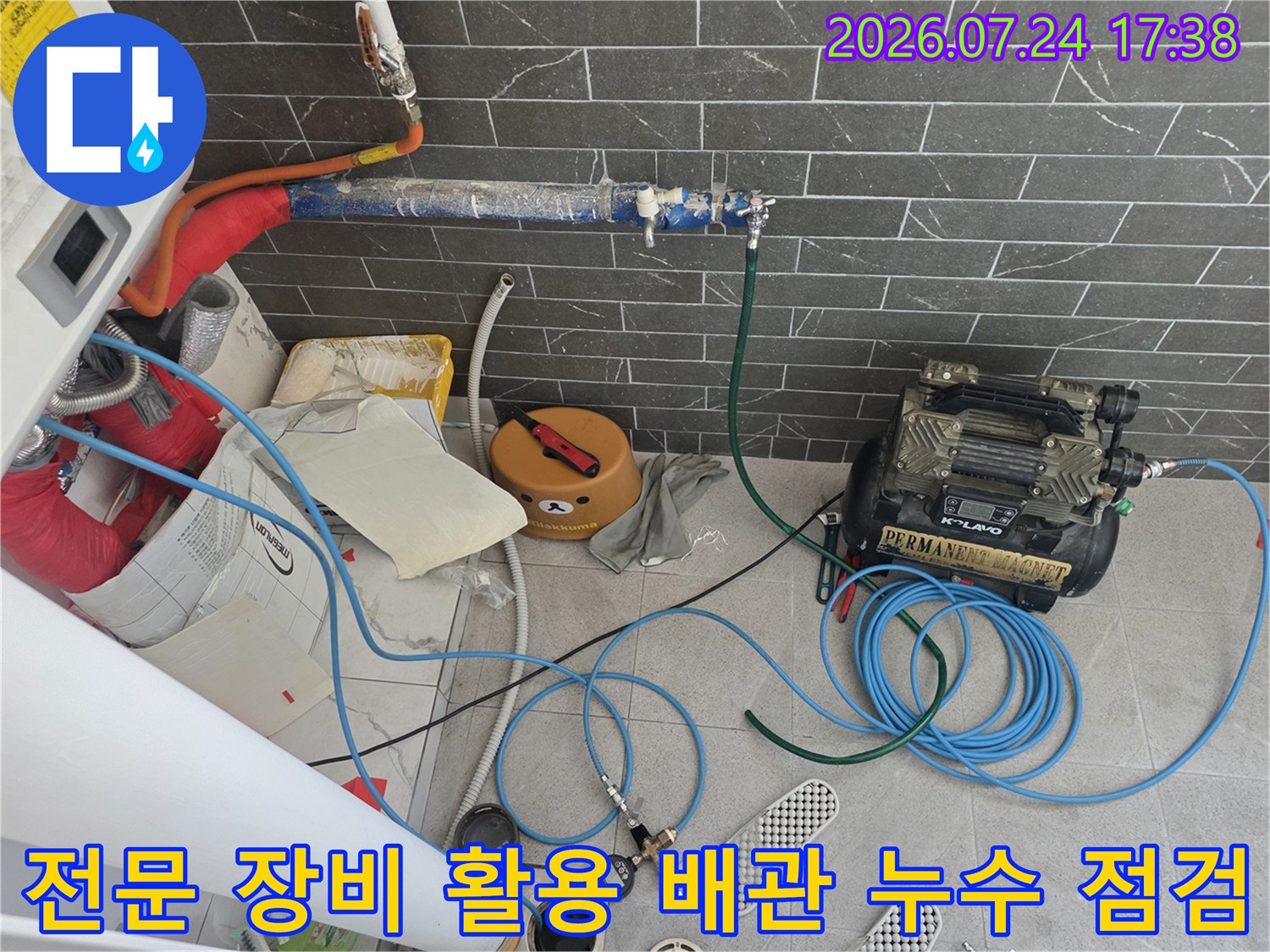 콤프레샤와 여러 호스를 연결하여 배관 기밀 시험을 수행하는 전문 기술 장면