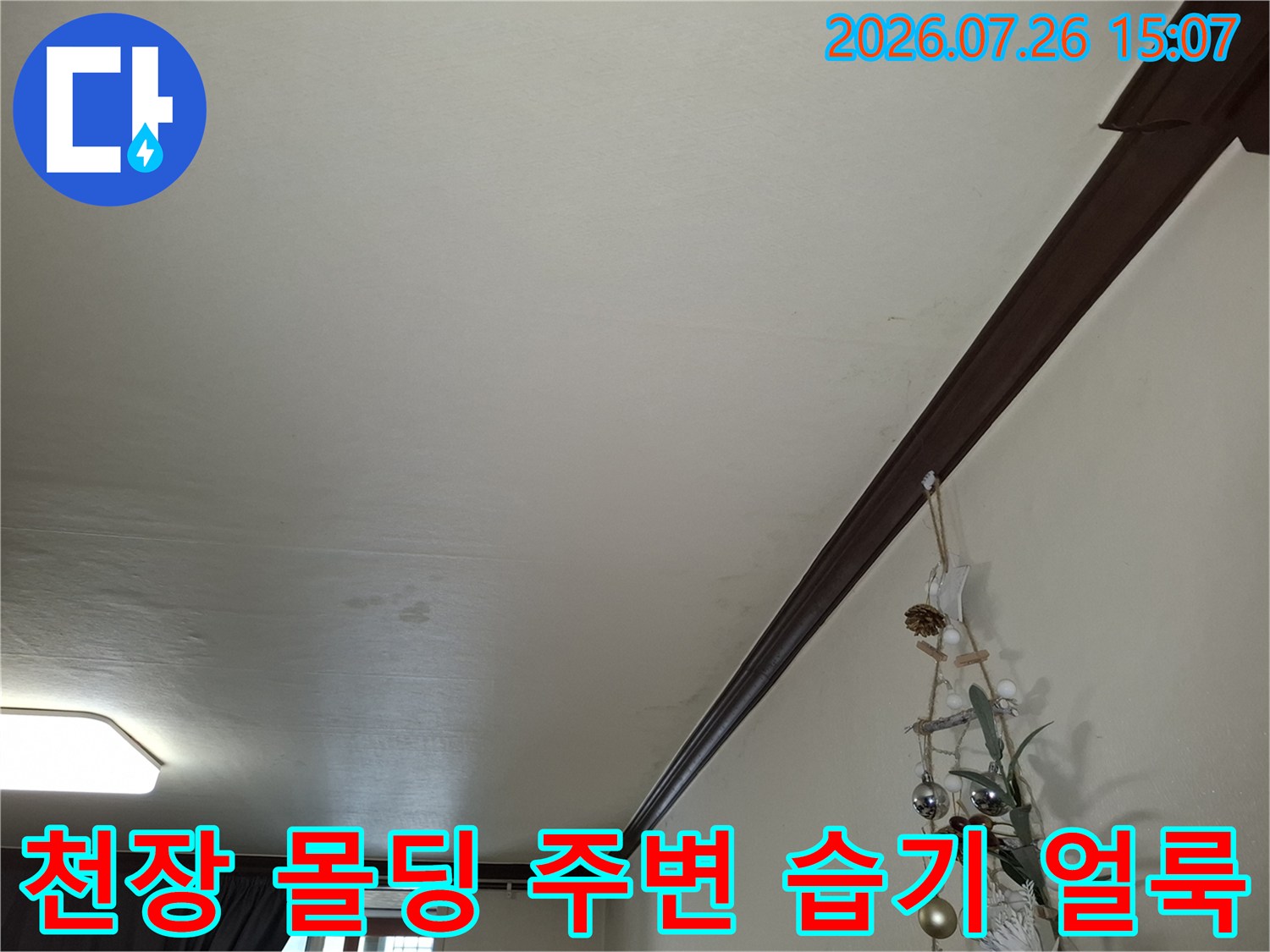거실 천장 구석 부분에 발생한 누수 흔적과 변색된 벽지 모습-사진