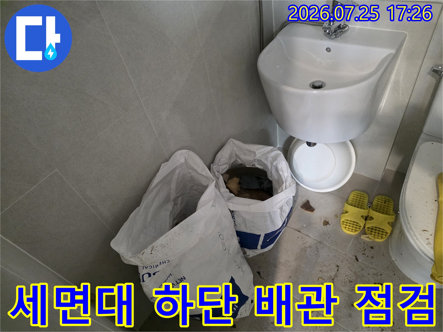 노출된 화장실 배관과 세면대 주변의 수선 준비 상태