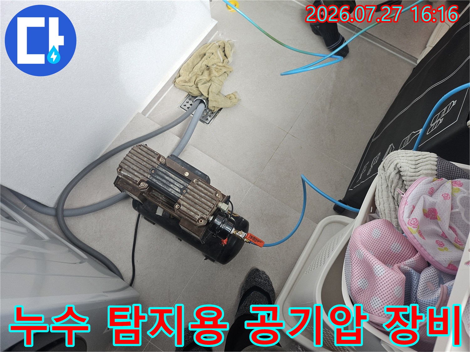 바닥에 놓인 전문적인 누수 탐지용 컴프레셔-장비와 파란색 호스 연결 모습