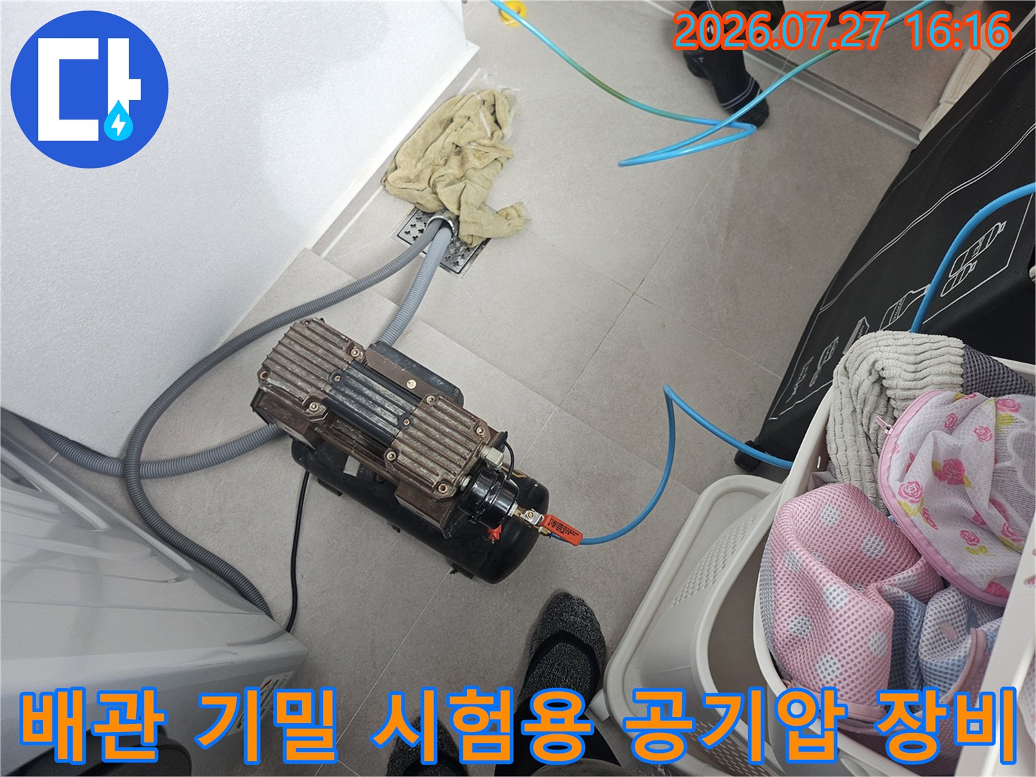 타일 바닥 위에 배치된 전문 누수 탐색 장비-파란색 호스 연결 상태