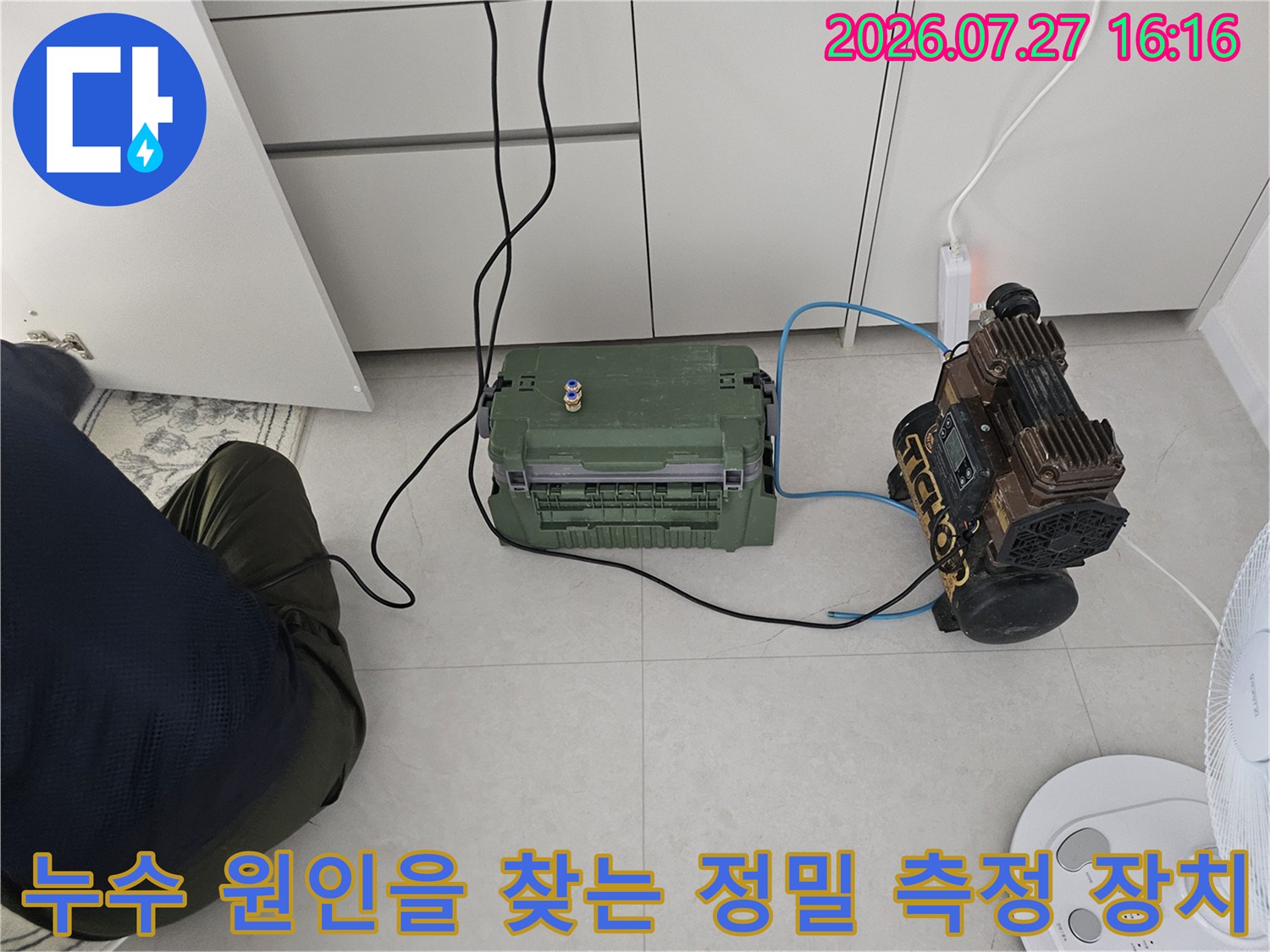 파란색 호스로 연결된 누수 진단용 기기와 녹색 플라스틱 공구함