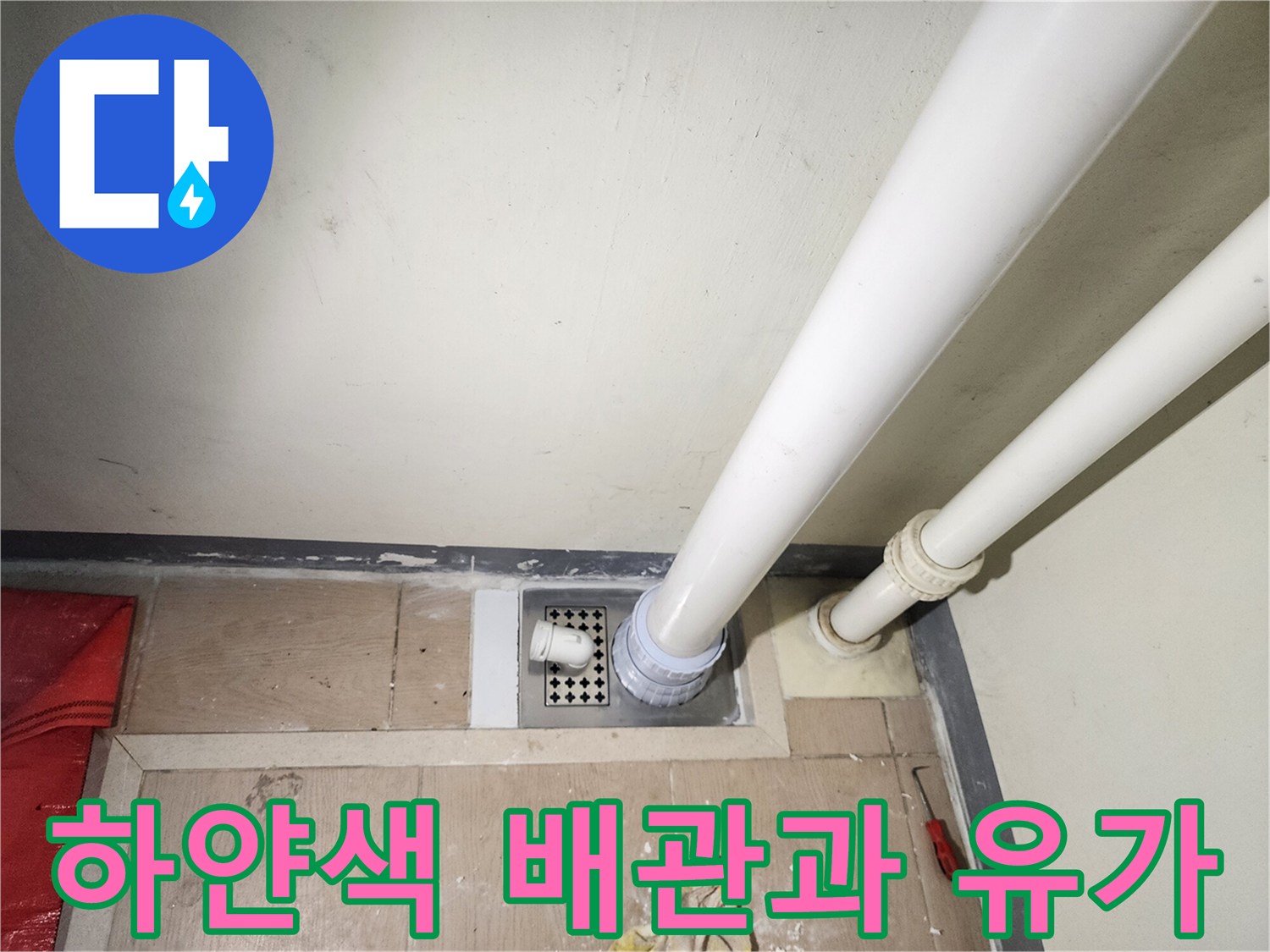 세탁실 바닥의 하얀색 배수 파이프와 배수구 덮개 모습입니다.
