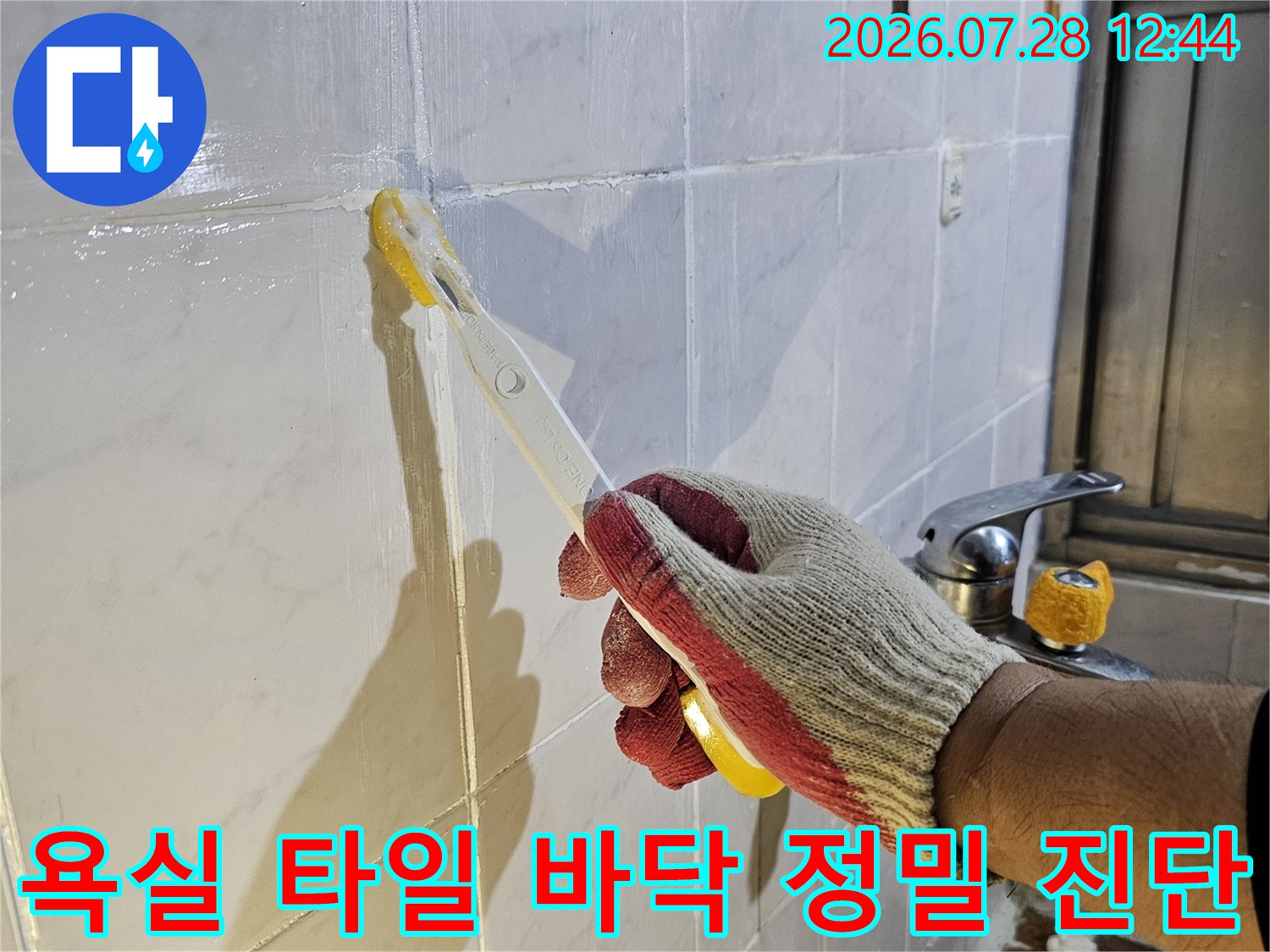 장갑을 낀 작업자가 타일 위에서 도구를 활용하여 점검하는 장면