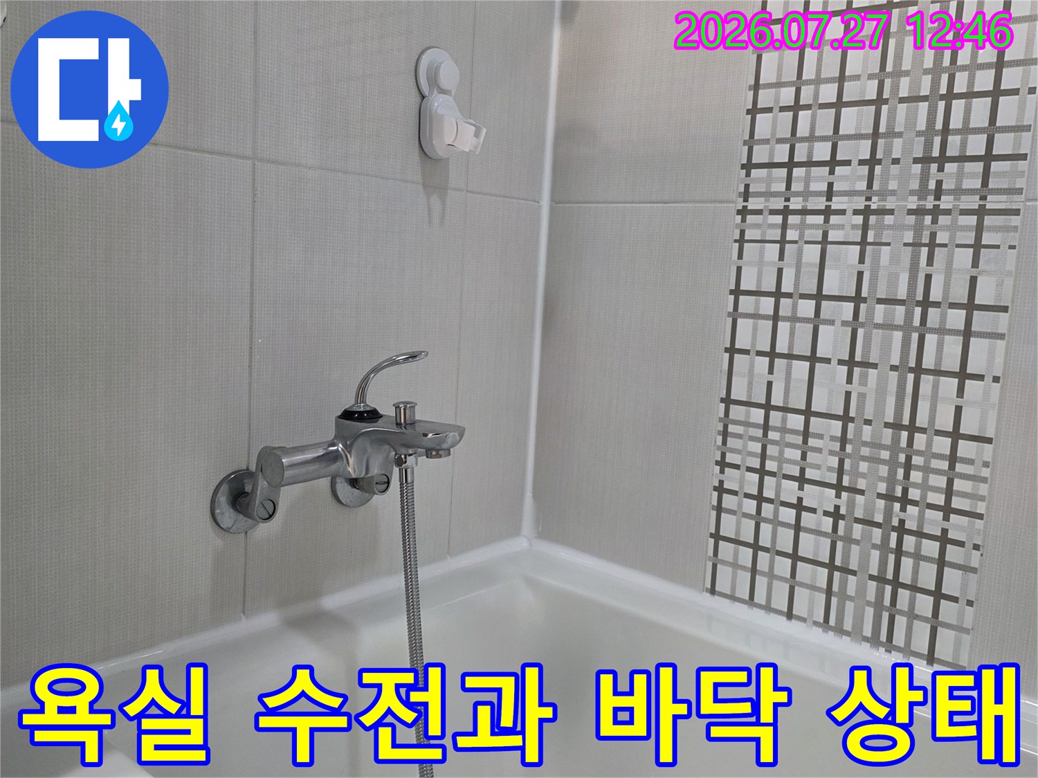 하얀색 타일이 설치된 욕실 내부에 샤워기 수전-배관 연결 부위가 보이는 모습