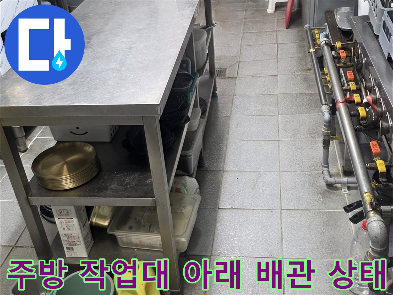상업용 주방 작업대 하단에 노출된 배관과 정비 도구들