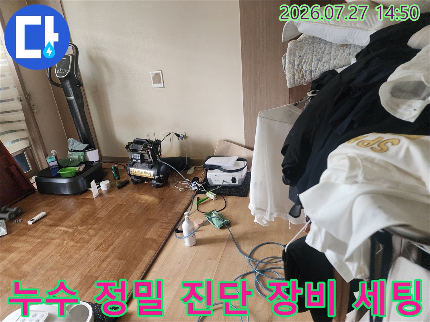 거실 바닥에 설치된 디지털 압력계와 공기 압축기-누수 탐지를 위한 전문 장비들