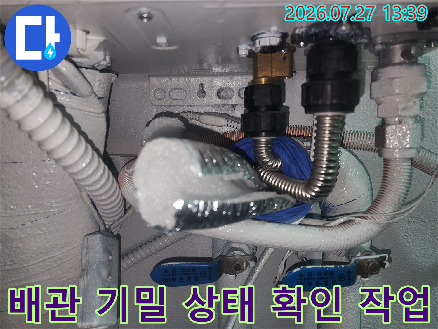 은색 주름관 배관과 검은색 플라스틱 부속-측정 장비가 연결된 보일러 하부 모습