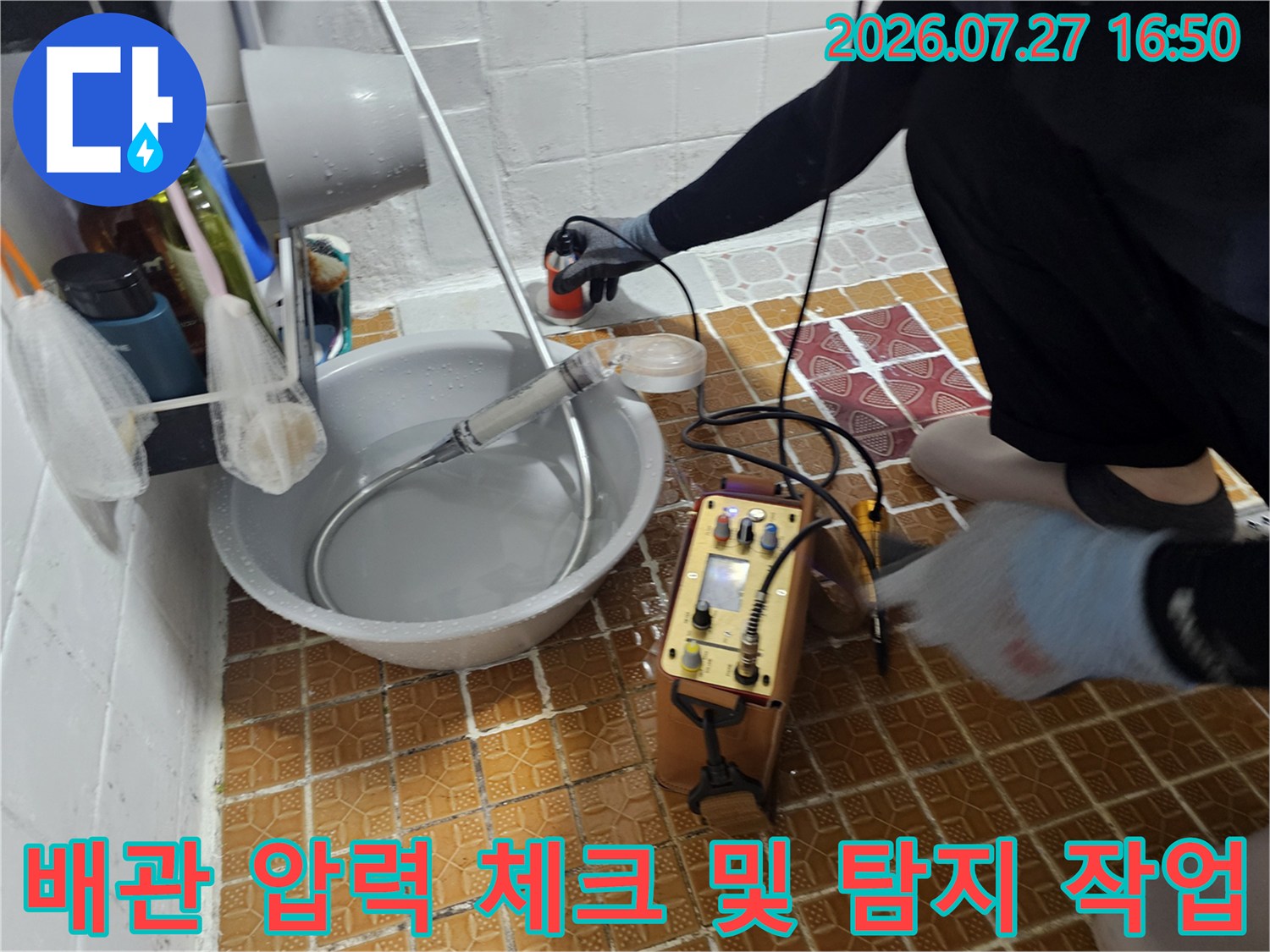 화장실 바닥에 설치된 누수 탐지 장비와 연결된 배관 호스 모습