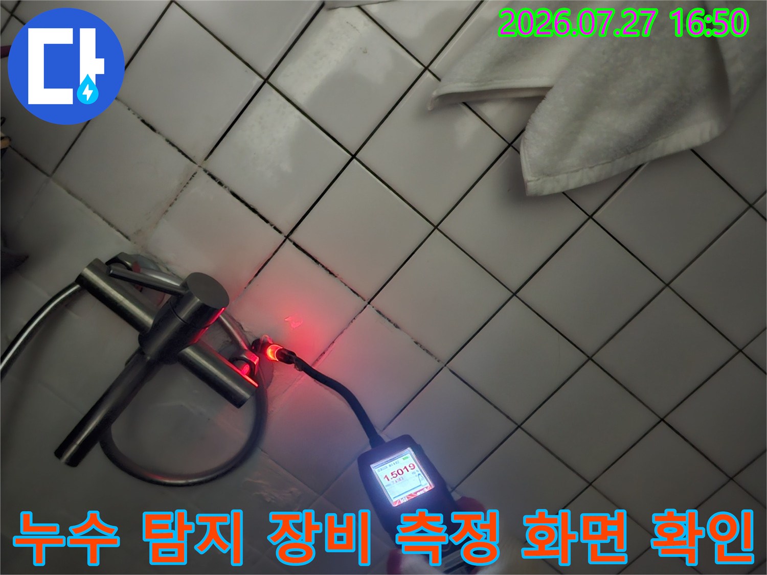 흰색 타일 배경의 화장실 천장에서 배관 누수를 감지하는 디지털 가스 탐지기 작동 모습