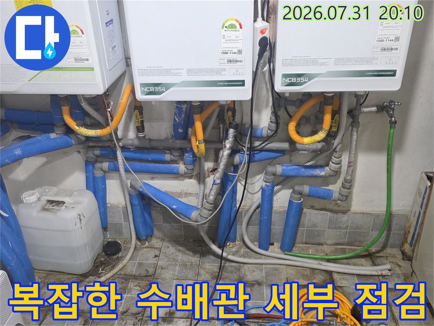 온수기 하단의 복잡하게 얽힌 배관망과 파란색 보온재가 덮인 수도 라인의 상세 모습