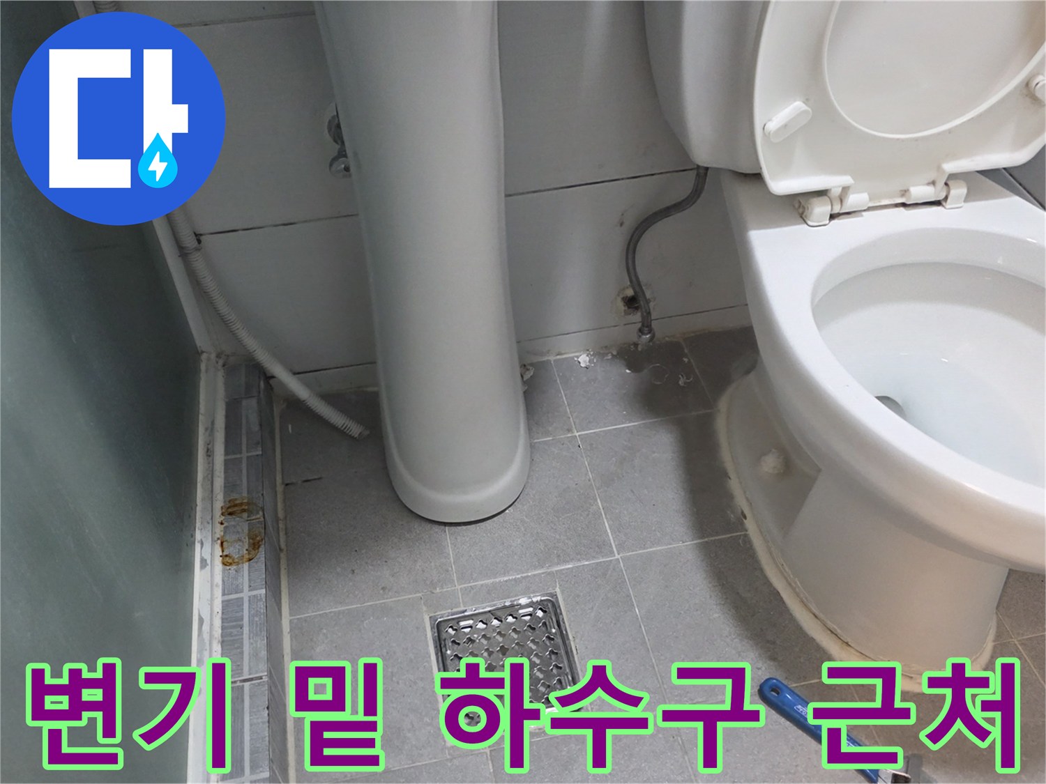 화장실 변기 옆 타일과 배수구가 보이는 모습입니다.