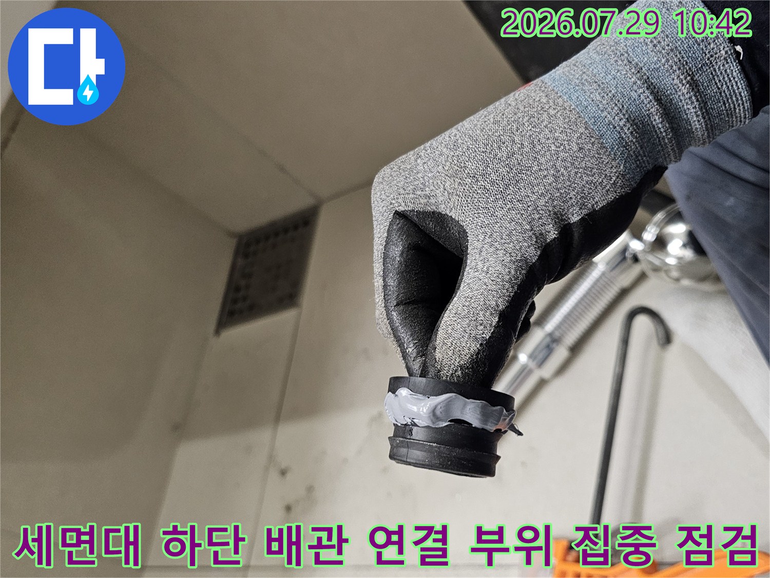 작업자가 세면대를 지탱하는 아래쪽 배관부의 결함 유무를 확인하는 사진