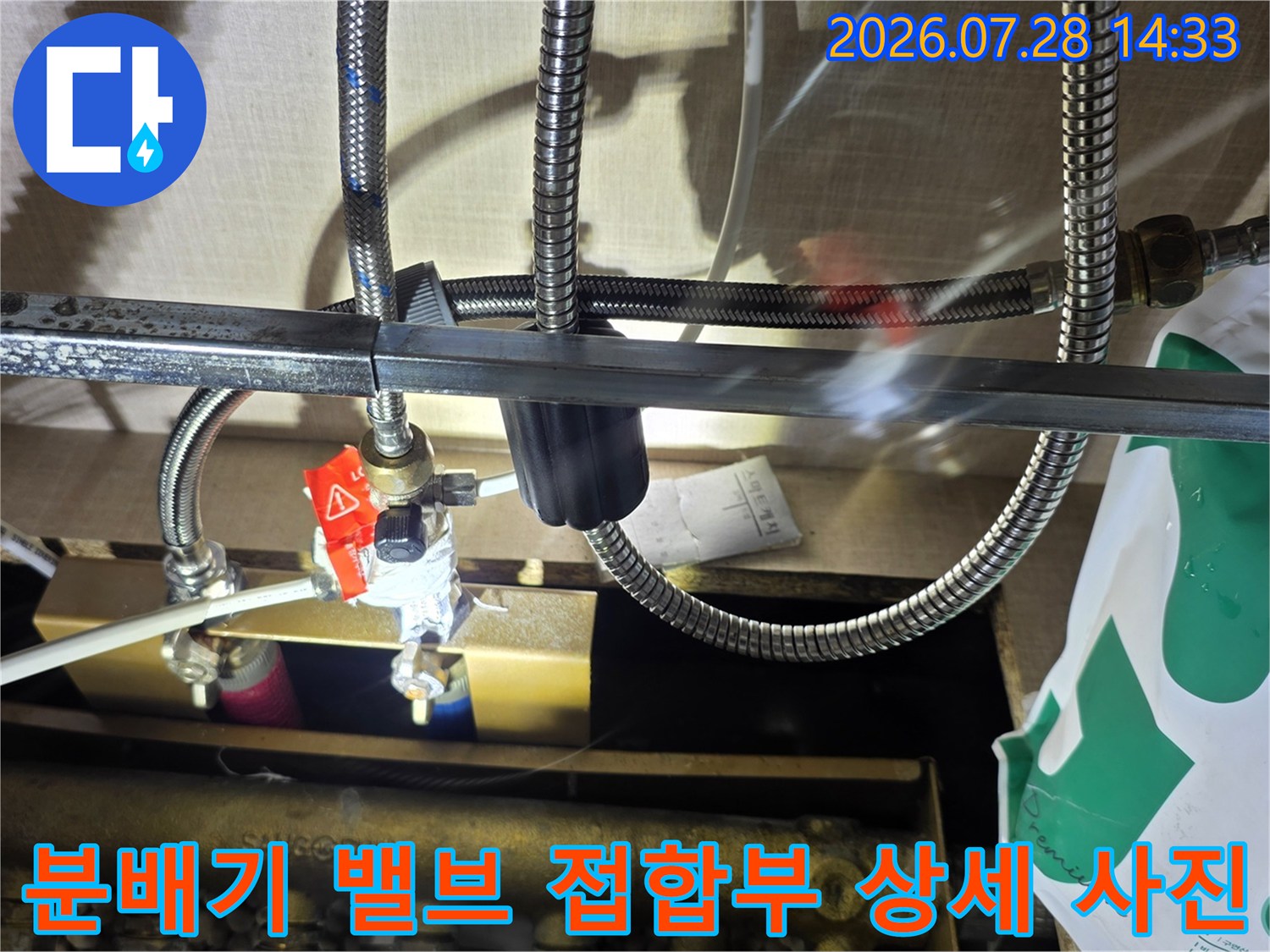 금속제 분배기와 빨간색 핸들 밸브 그리고 스테인리스 주름관의 연결 지점-누수 부위