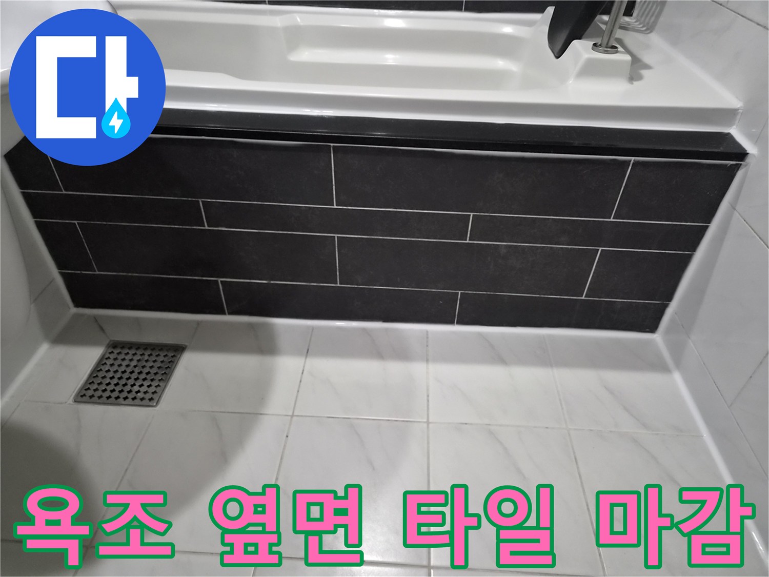 어두운 색상의 욕조 측면 타일과 화이트 바닥 타일의 경계