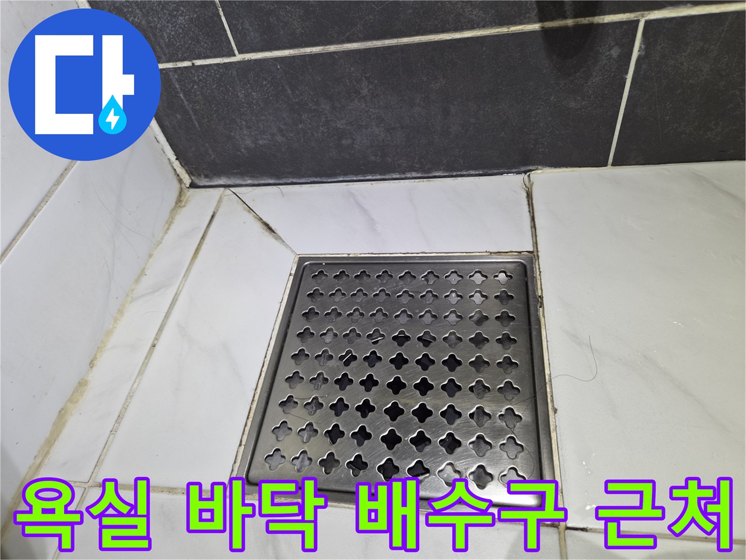 화이트 타일과 다크 그레이 타일 경계의 배수구 모습입니다.