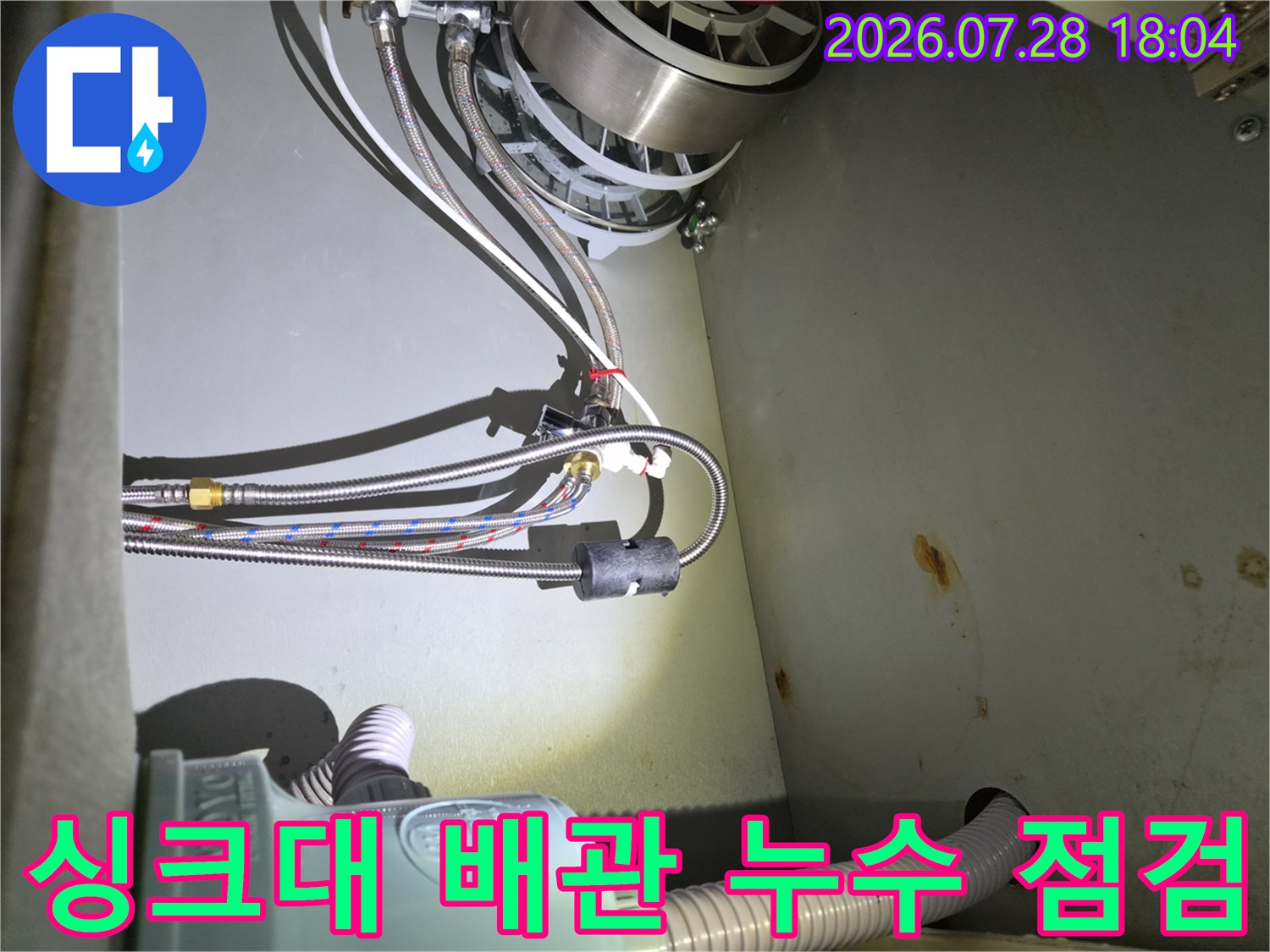 식기세척기와 연결된 싱크대 하부장 내부의 복잡한 배관 구조와 연결 부위 상태