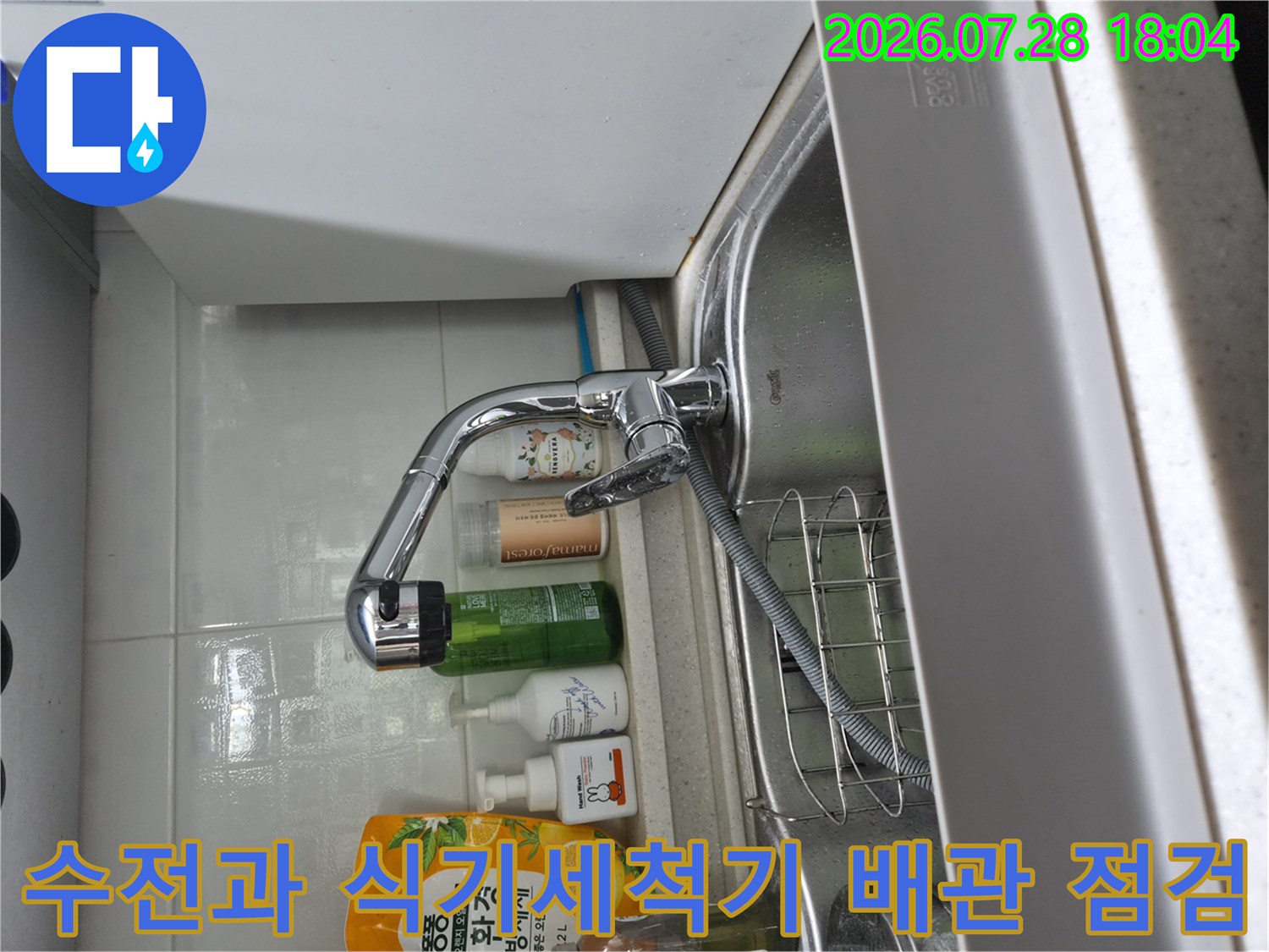 싱크대 아래 수전 및 식기세척기용 분기 배관의 연결 상태를 정밀하게 확인하는 사진