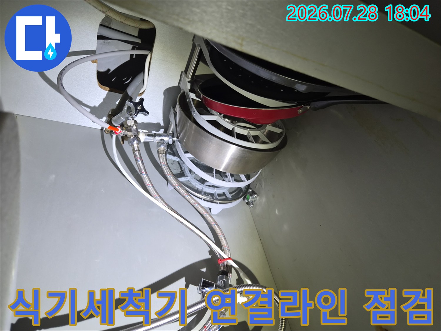 싱크대 하부장의 좁은 공간에서 노출된 배관과 어댑터 부품들을 정밀 진단하는 모습