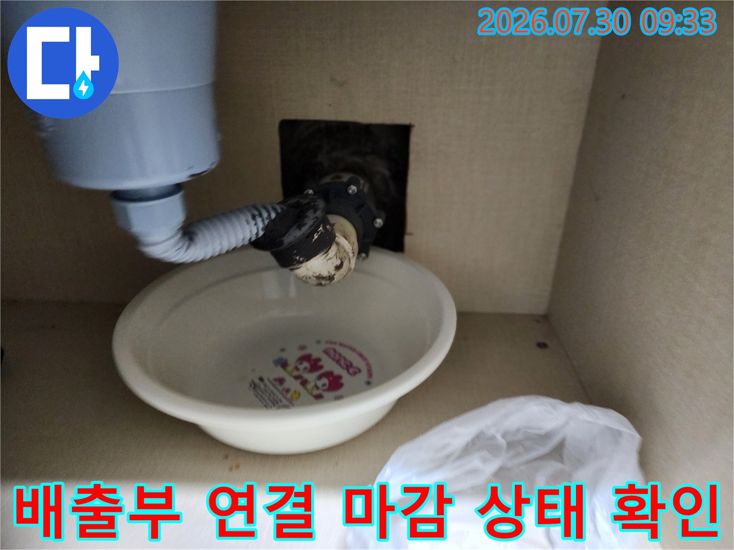 싱크대 하단 배출구와 호스 사이의 마감 불량을 점검하는 현장 사진입니다.