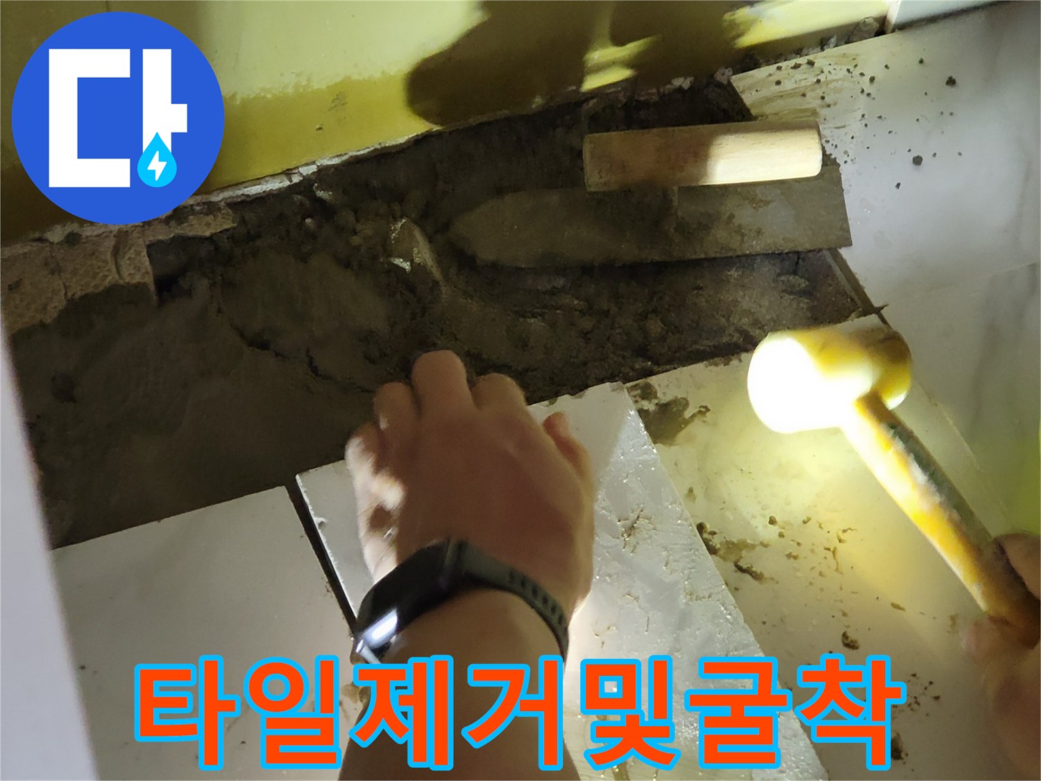 타일 조각을 걷어내고 바닥 시멘트를 파헤치는 공사 장면입니다.
