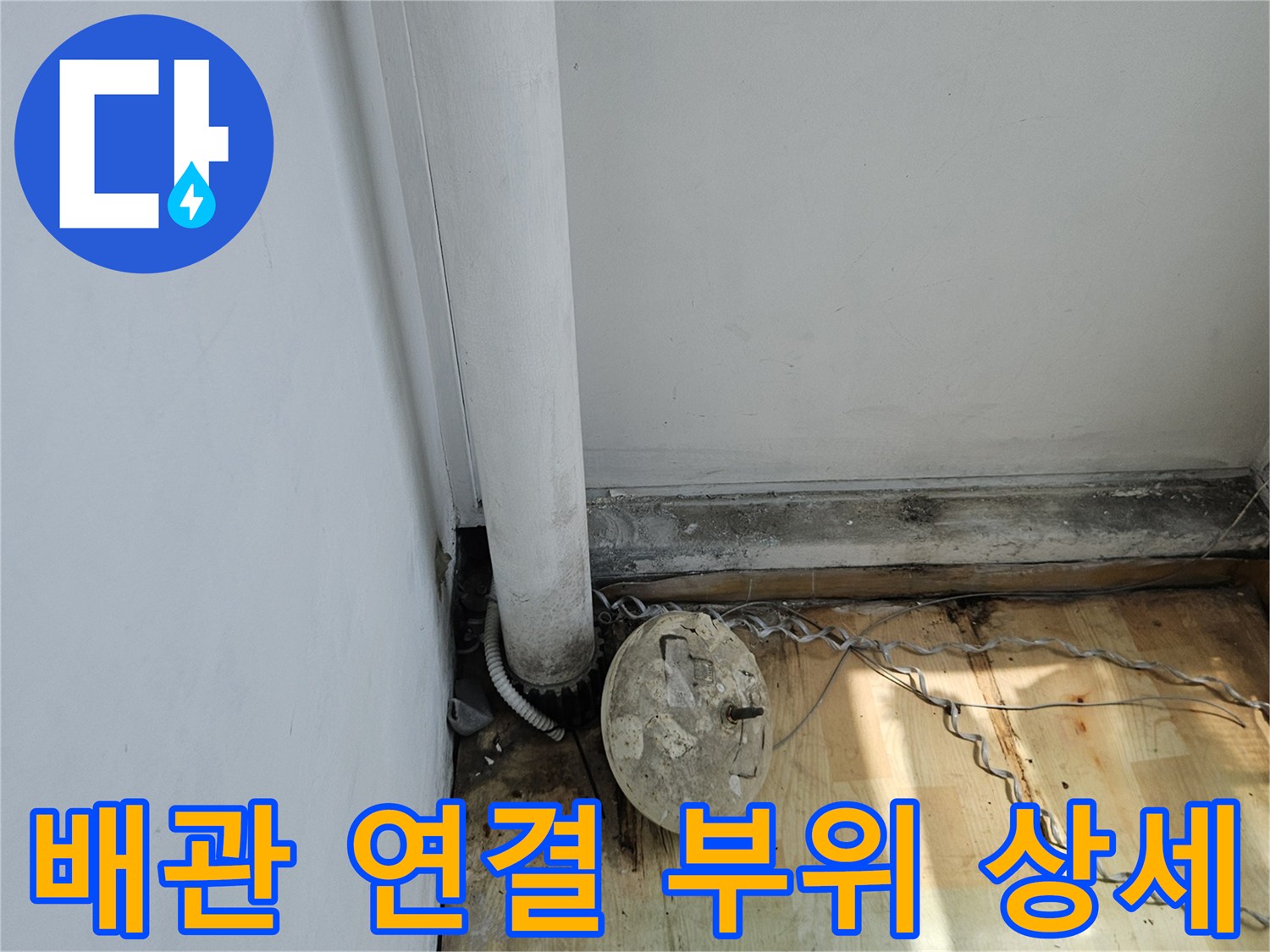 목재 벽면과 흰색 배관이 만나는 연결 지점의 근접 촬영