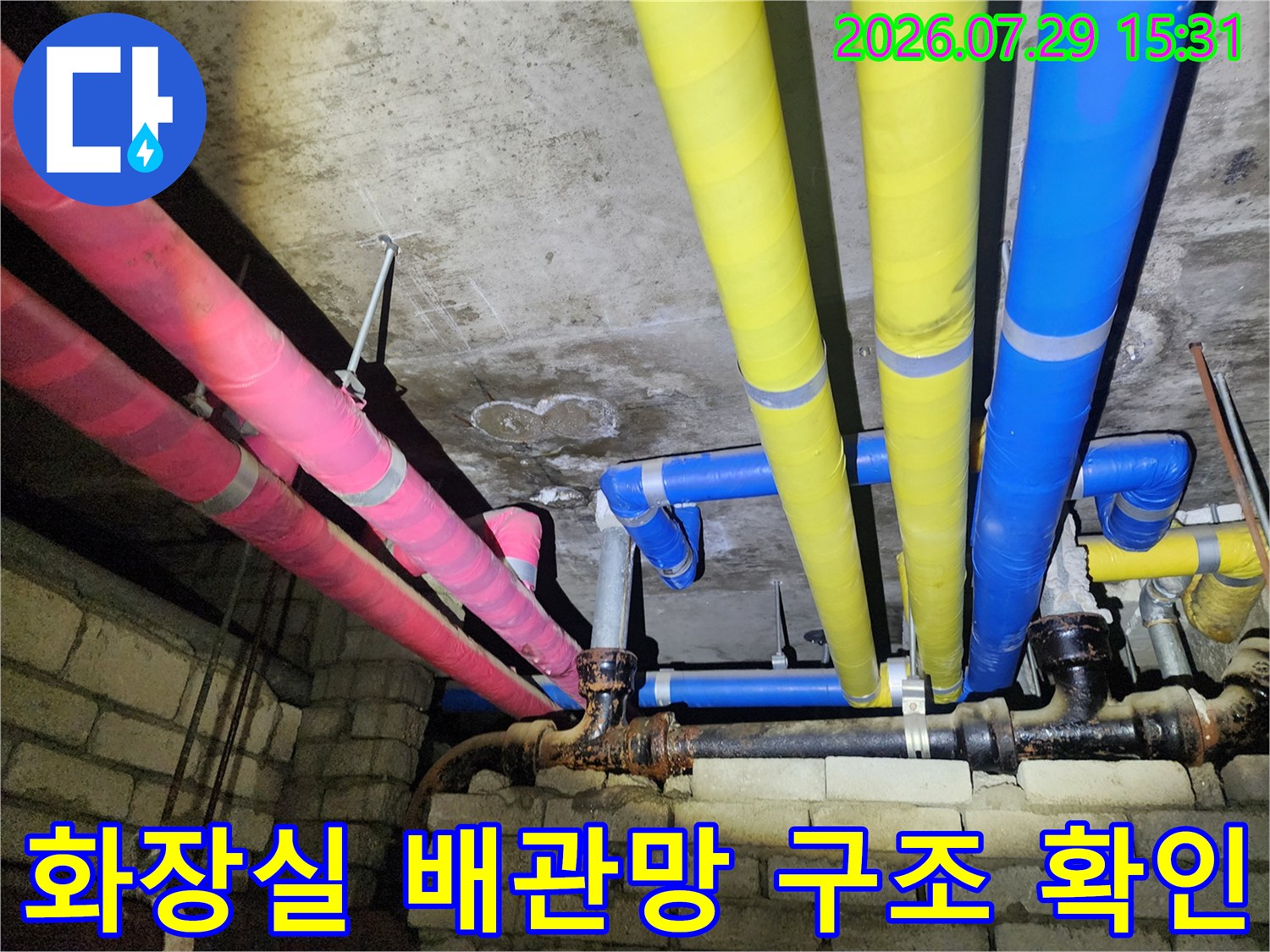 다양한 색상의 보온재로 마감된 천장 내 배관 시스템의 점검 장면입니다.