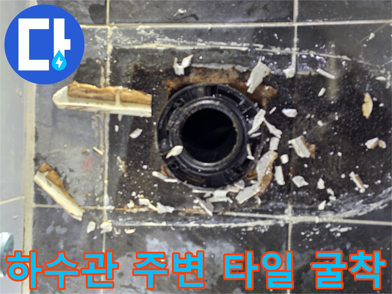 화장실 하수관 입구 부근의 파손된 타일과 노출된 배관