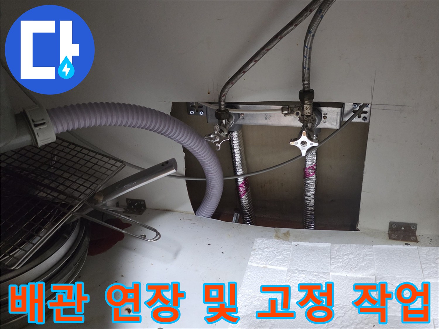 새로 교체한 은색 배관과 밸브가 포함된 싱크대 하부 설비 모습입니다.