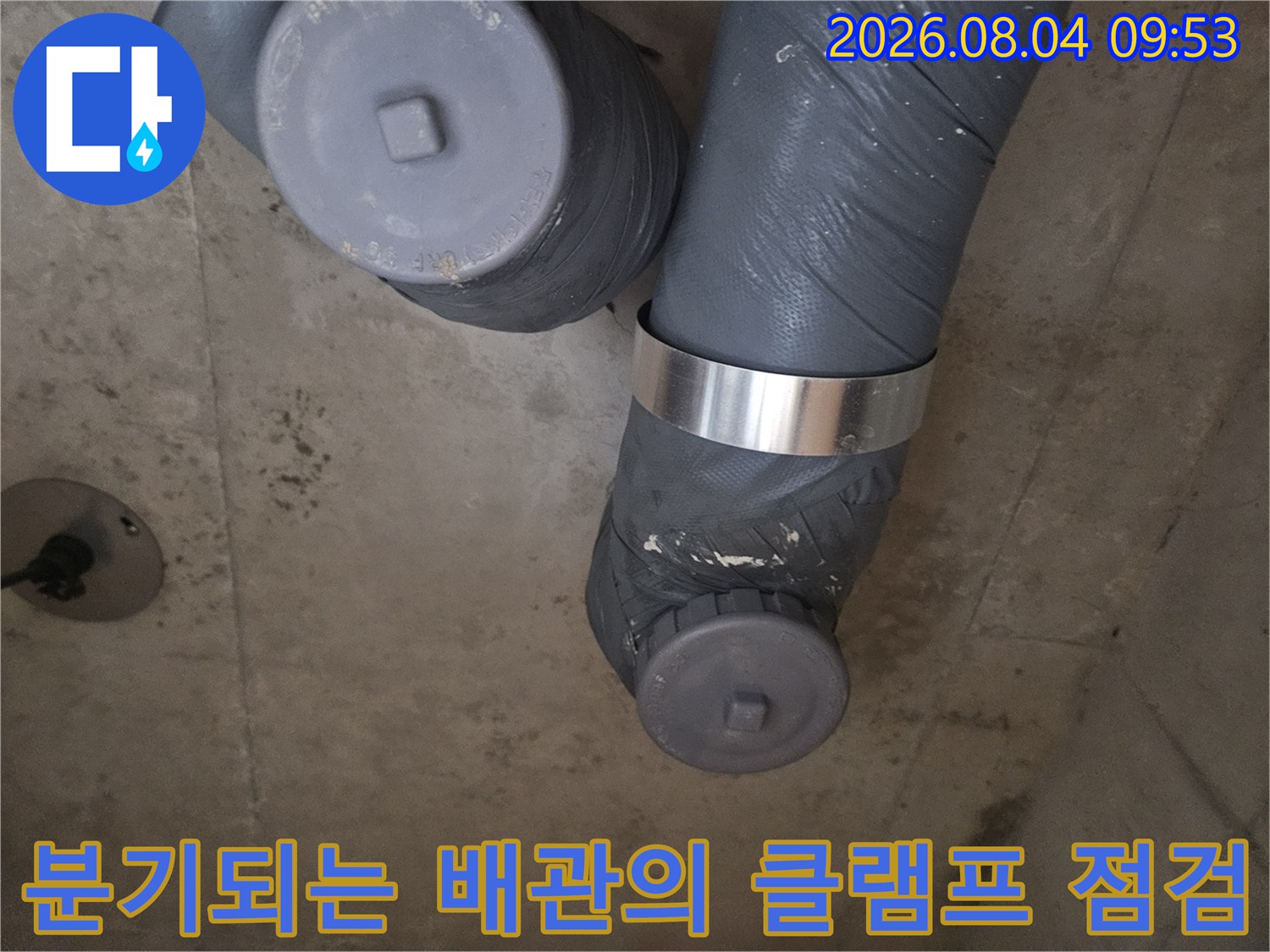 보온재를 벗겨내고 노출된 배관 연결부와 고정 장치를 확인하는 모습